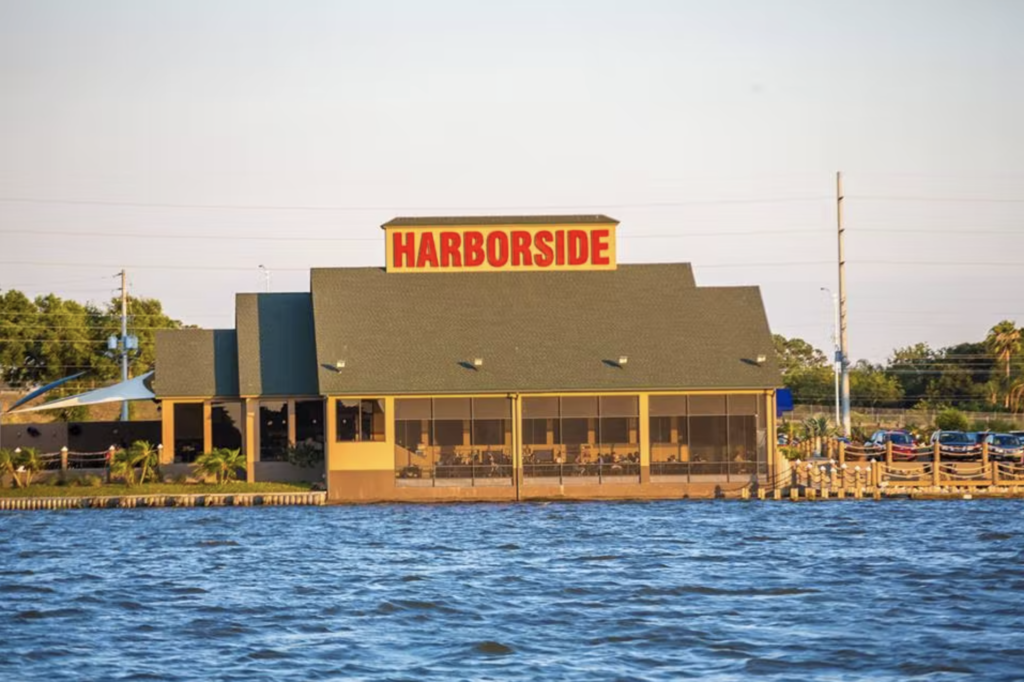 Large Harborside sign on top of a single story building directly on a lake.